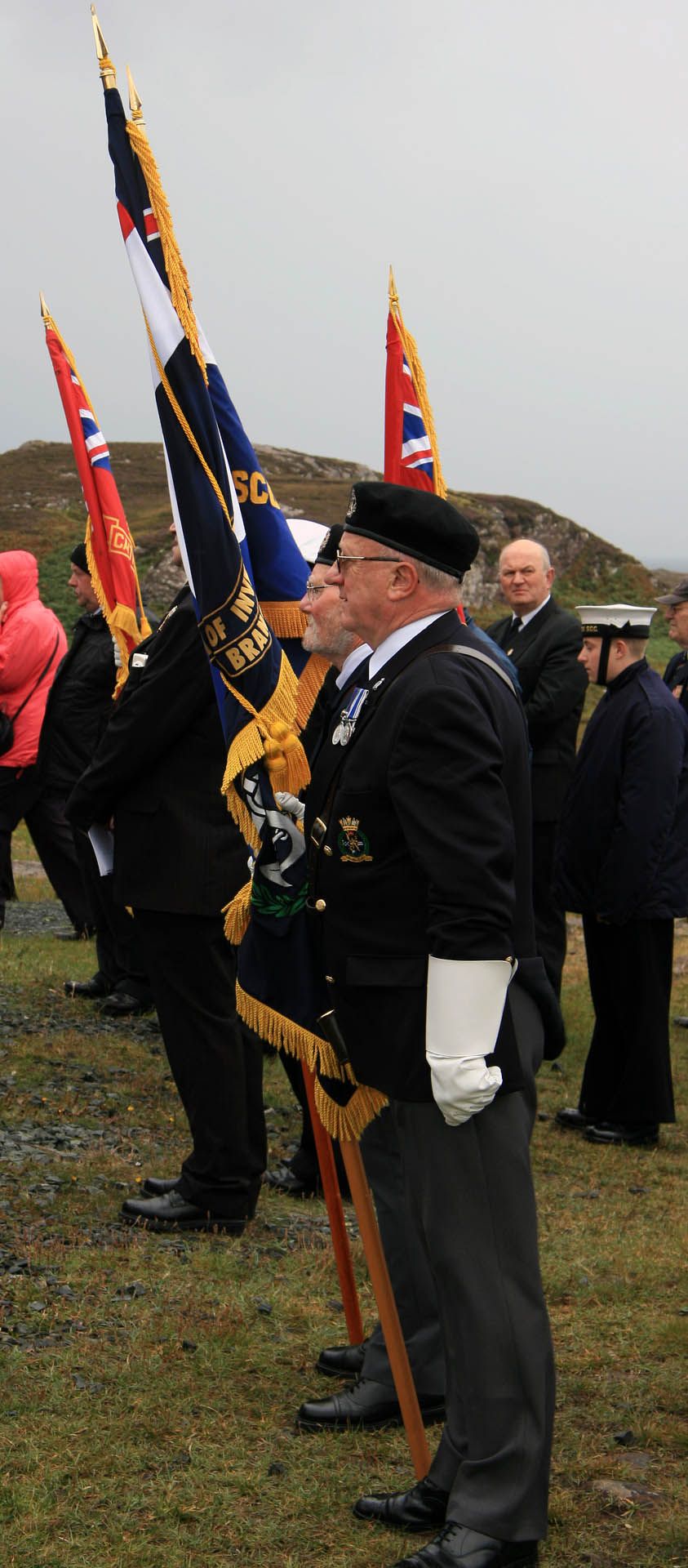 A picture of a parade of veterans and service personnel at the Arctic Convoy Monument Aultbea, Gairloch. The picture features military personal holding flags.