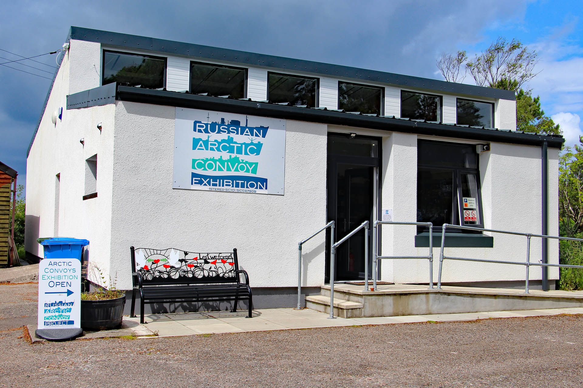 A picture of the outside of the Arctic Convoy Museum Aultbea, Gairloch. The museum is modern in design and white washed. There is a ramped disabled entrance at the front of the building