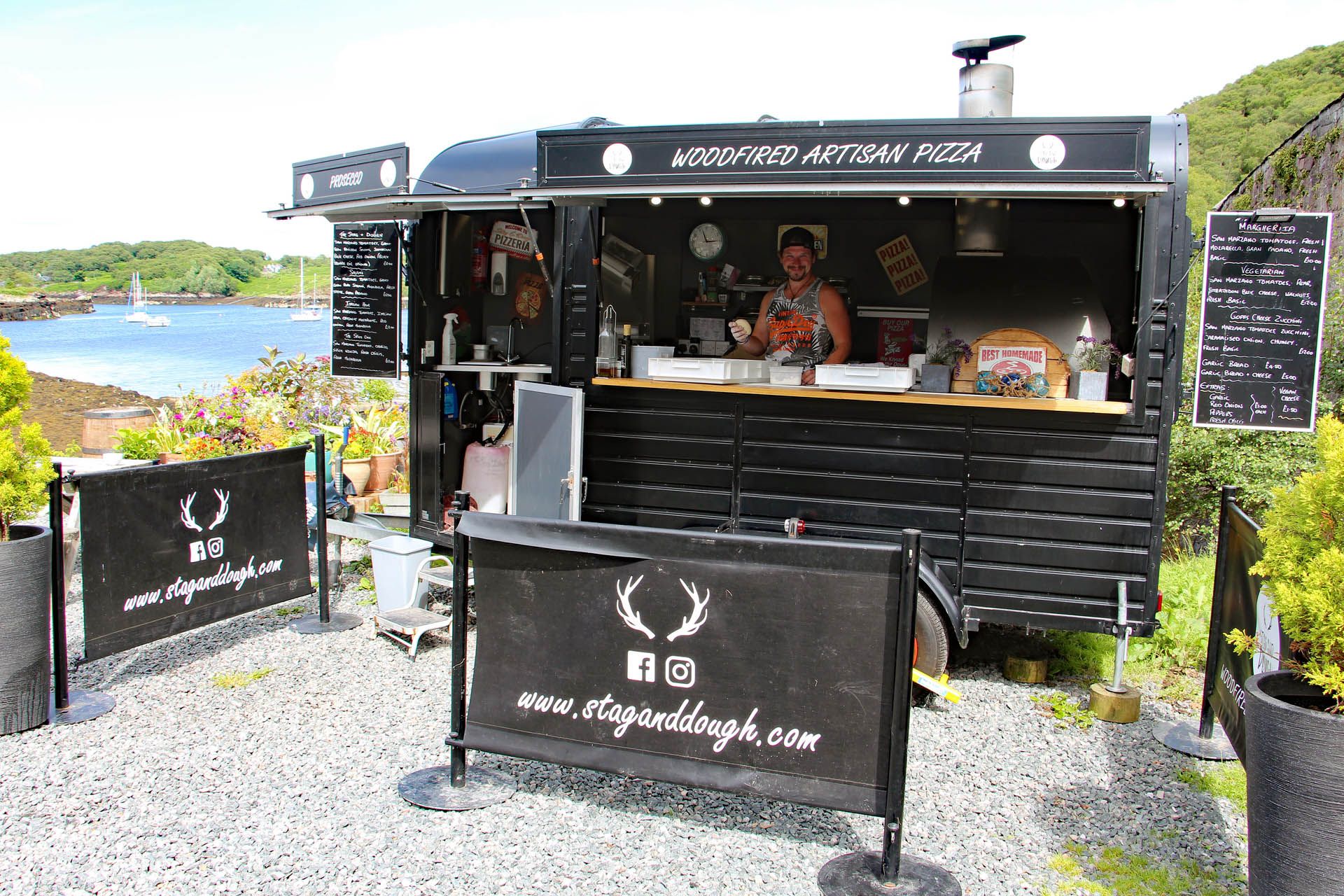 A picture of the Stag & Dough mobile pizza bar set in the premises of the Badachro Inn in Gairloch. The picture includes a chef within the mobile pizza bar.