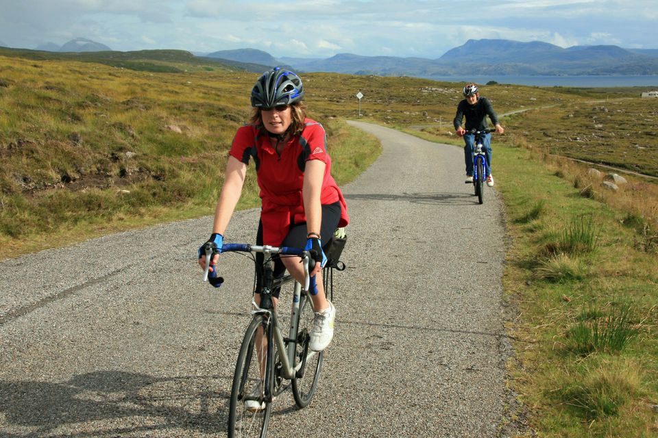 A man and a woman cycling up a hill near Red Point in Gairloch