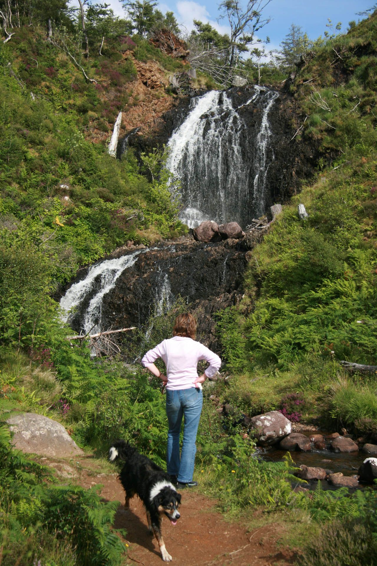 A picture of Flowerdale Falls in Gairloch. The picture includes a woman walking a dog