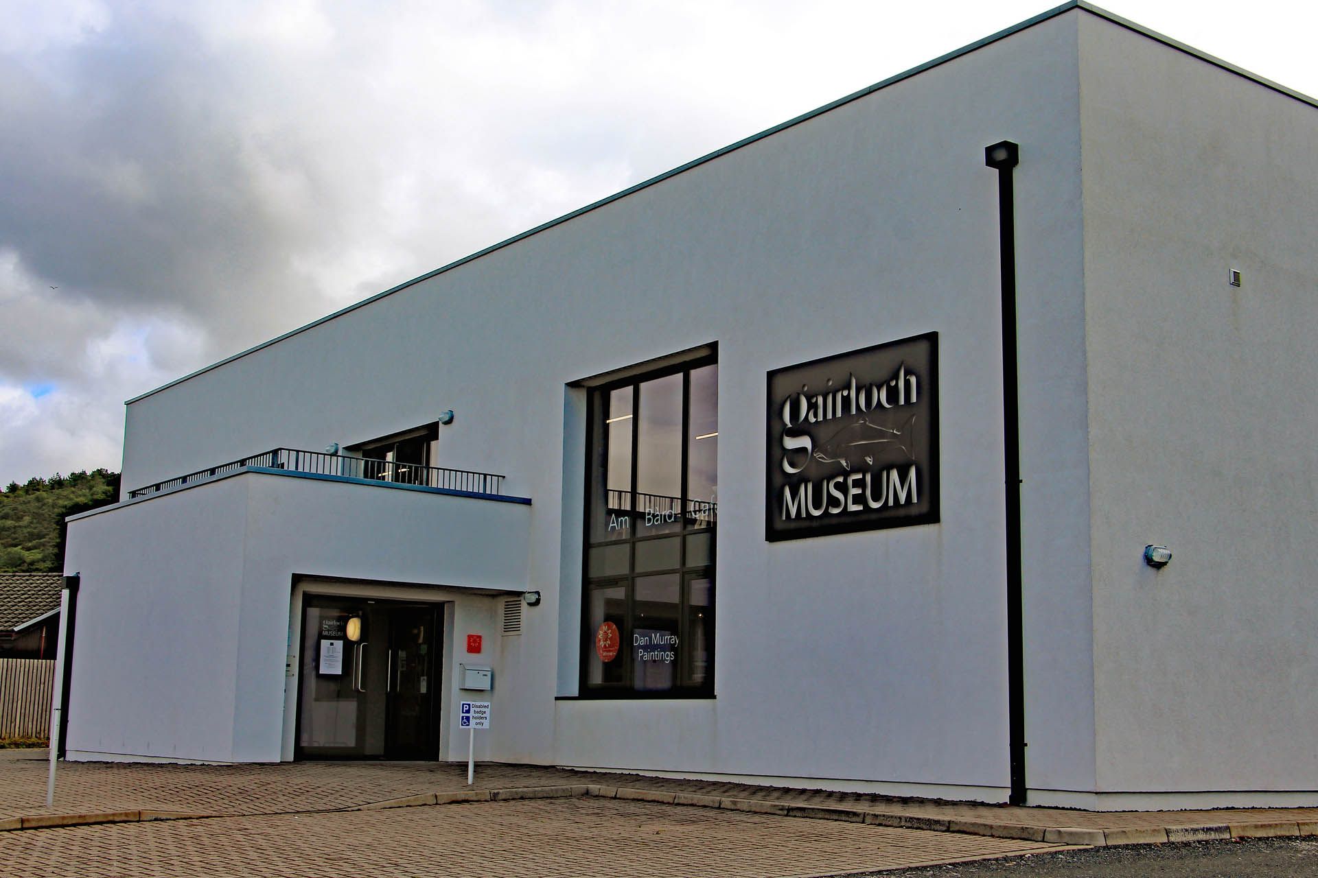 A picture of the outside of the Gairloch museum. The museum is modern in design and white washed. There is disabled parking at the entrance of the building