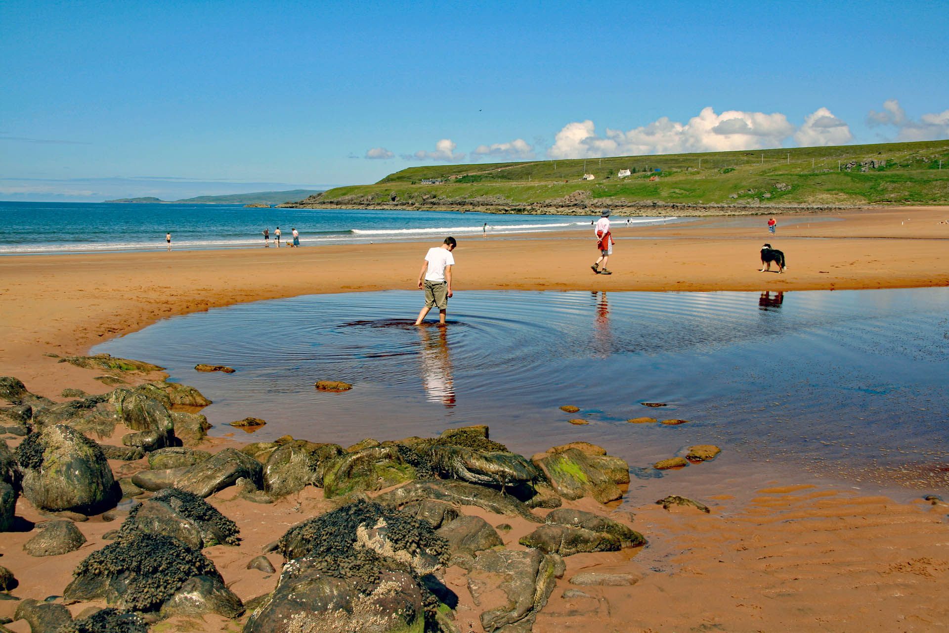 People playing and walking on Red Point Beach in Gairloch