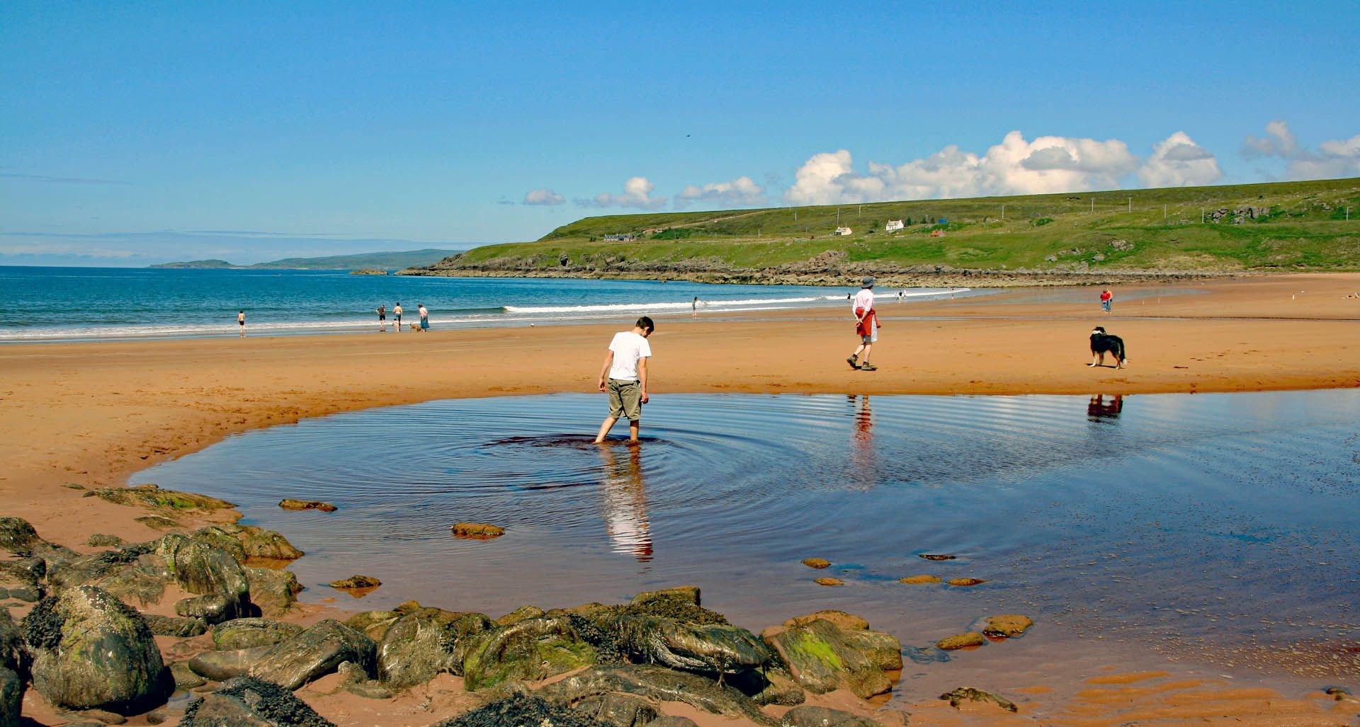 People playing and walking on Red Point Beach in Gairloch